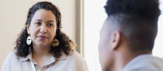 A female counselor listens to a young adult and takes notes for their next meeting