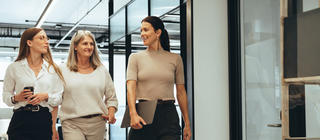 Three cheerful businesswomen walking together in an office.
