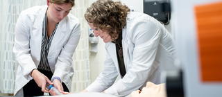 A professor trains a Physician Assistant student on injecting saline