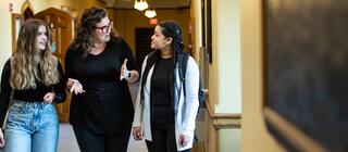 A professor walks with two undergraduate students down a hallway in Barbelin on Hawk Hill campus