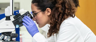 A School of Health Professions student analyzes test results through a microscope
