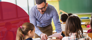 Male teacher helps students at their desks in an elementary school classroom