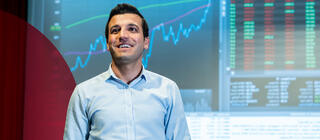 A young man wearing a collared shirt presents data visualizations via a projector