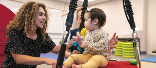 An occupational therapist works with a small child on balance