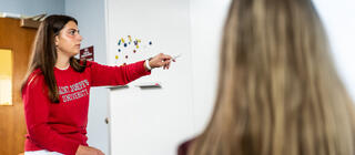 Student works out communication strategy on whiteboard with classmate