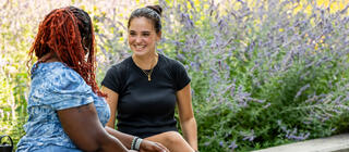 Two students connect sitting outside on Hawk Hill campus