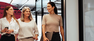 Three cheerful businesswomen walking together in an office.