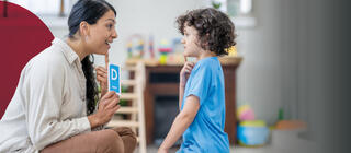A female speech therapist works with a boy practicing sounds and letter enunciation