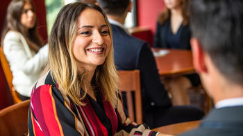 A female graduate students sits chatting with a classmate in Mandeville Hall